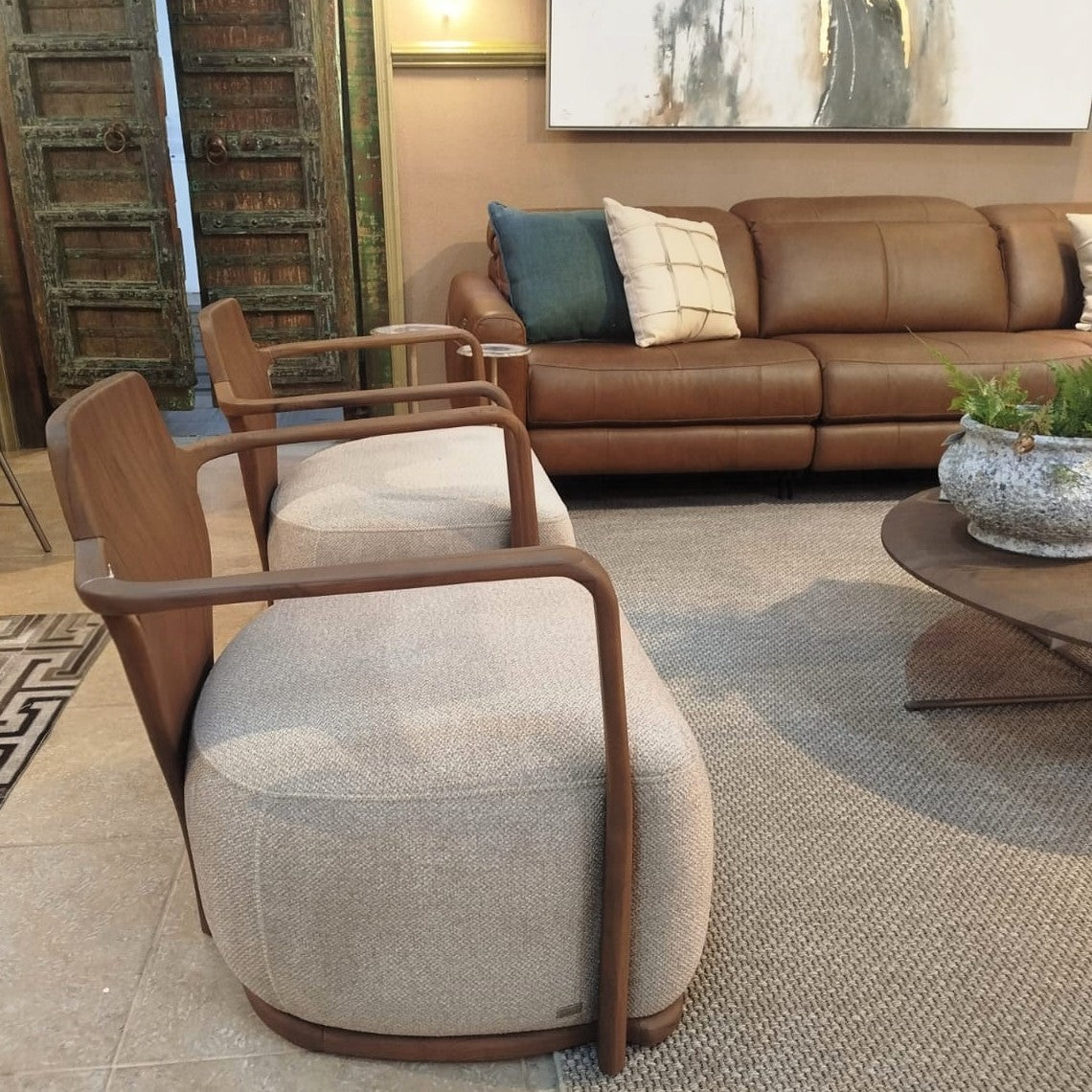 Modern living room with a brown leather sofa, gray upholstered chair, and decorative elements.