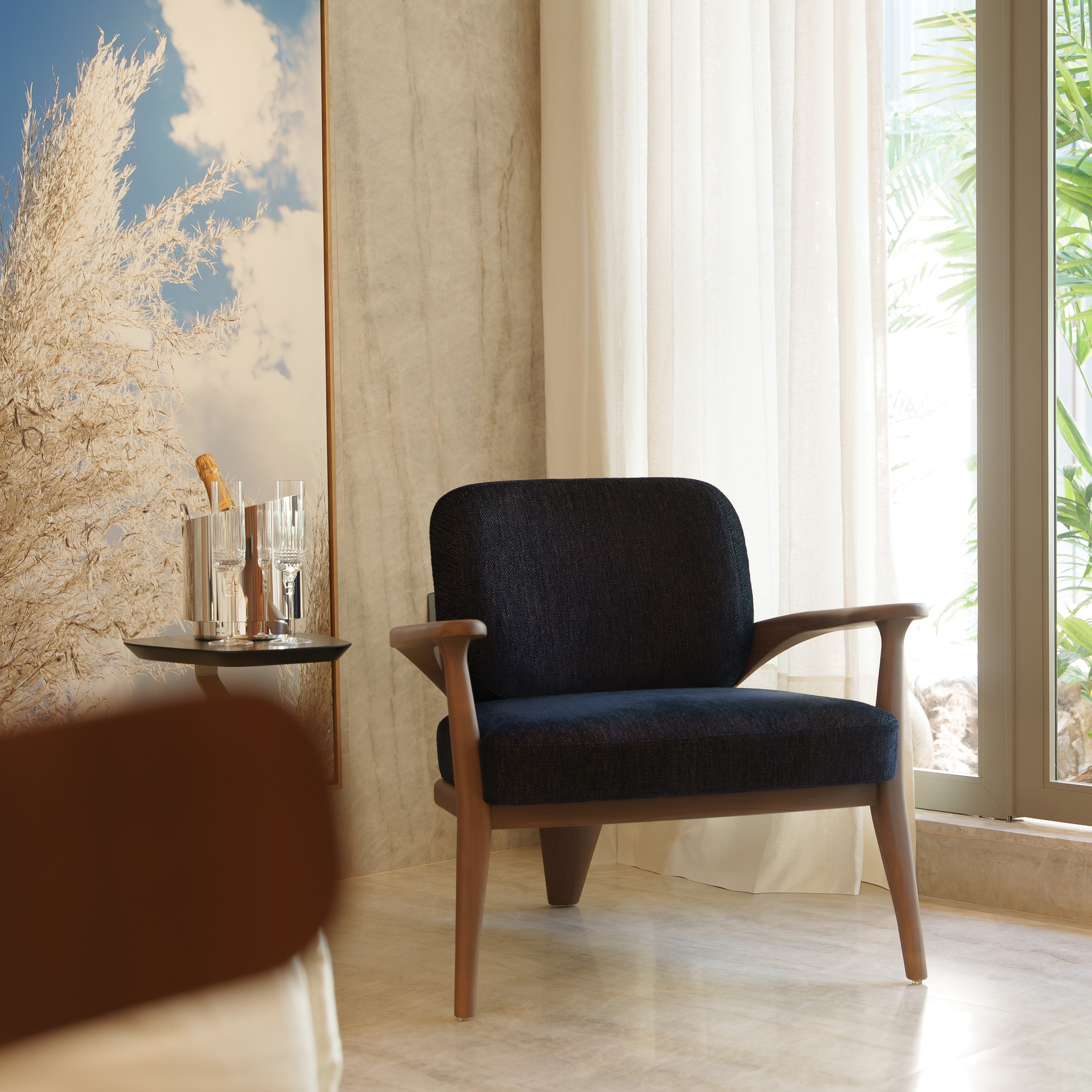 Black armchair in a room with a large window and decorative wall art.