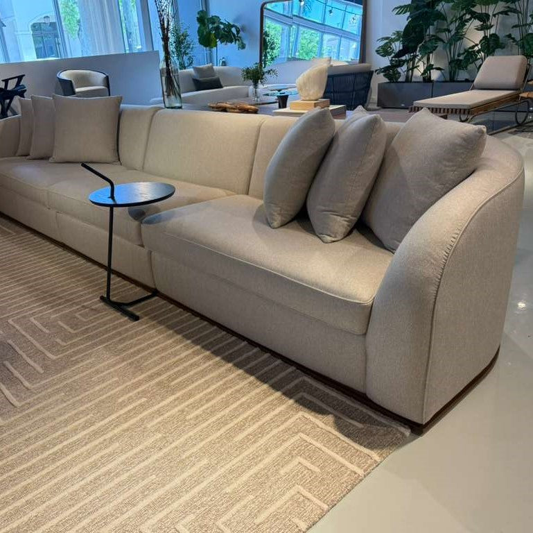 Beige sectional sofa in a modern living room with decorative pillows and a small round table.