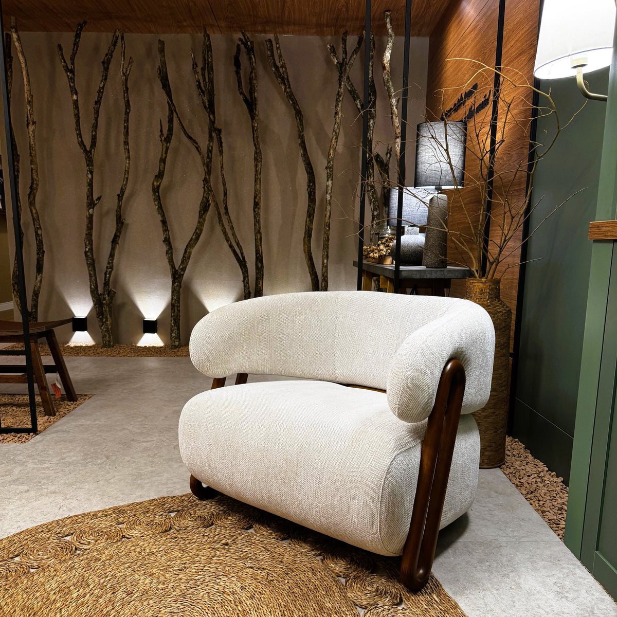 White armchair with wooden legs in a room with decorative wall and lighting