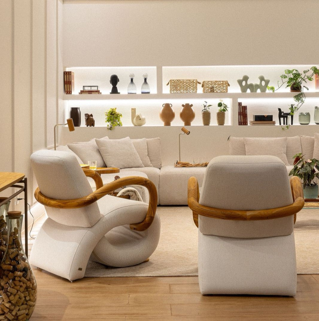 Modern living room with white sofa, armchairs with wooden armrests, and a shelf in the background.