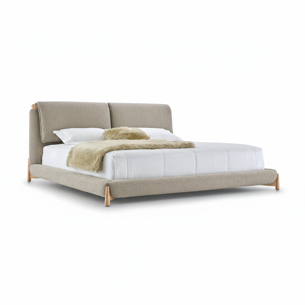 Beige upholstered bed with white bedding and a green throw on a white background
