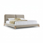 Beige upholstered bed with white bedding and a green throw on a white background