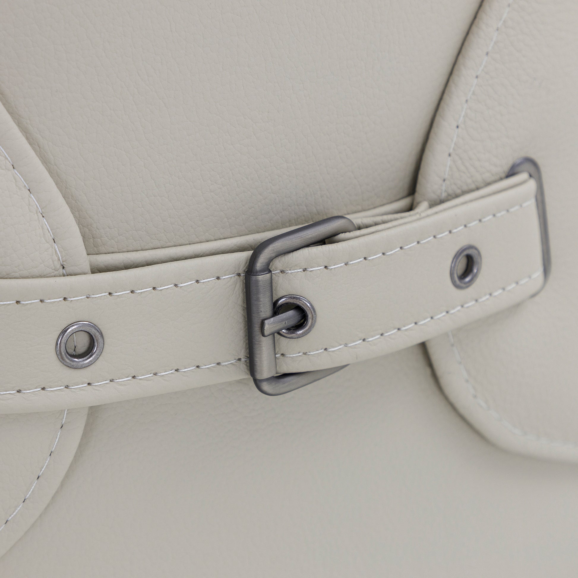 Close-up of a light gray leather bag with a strap and buckle detail.