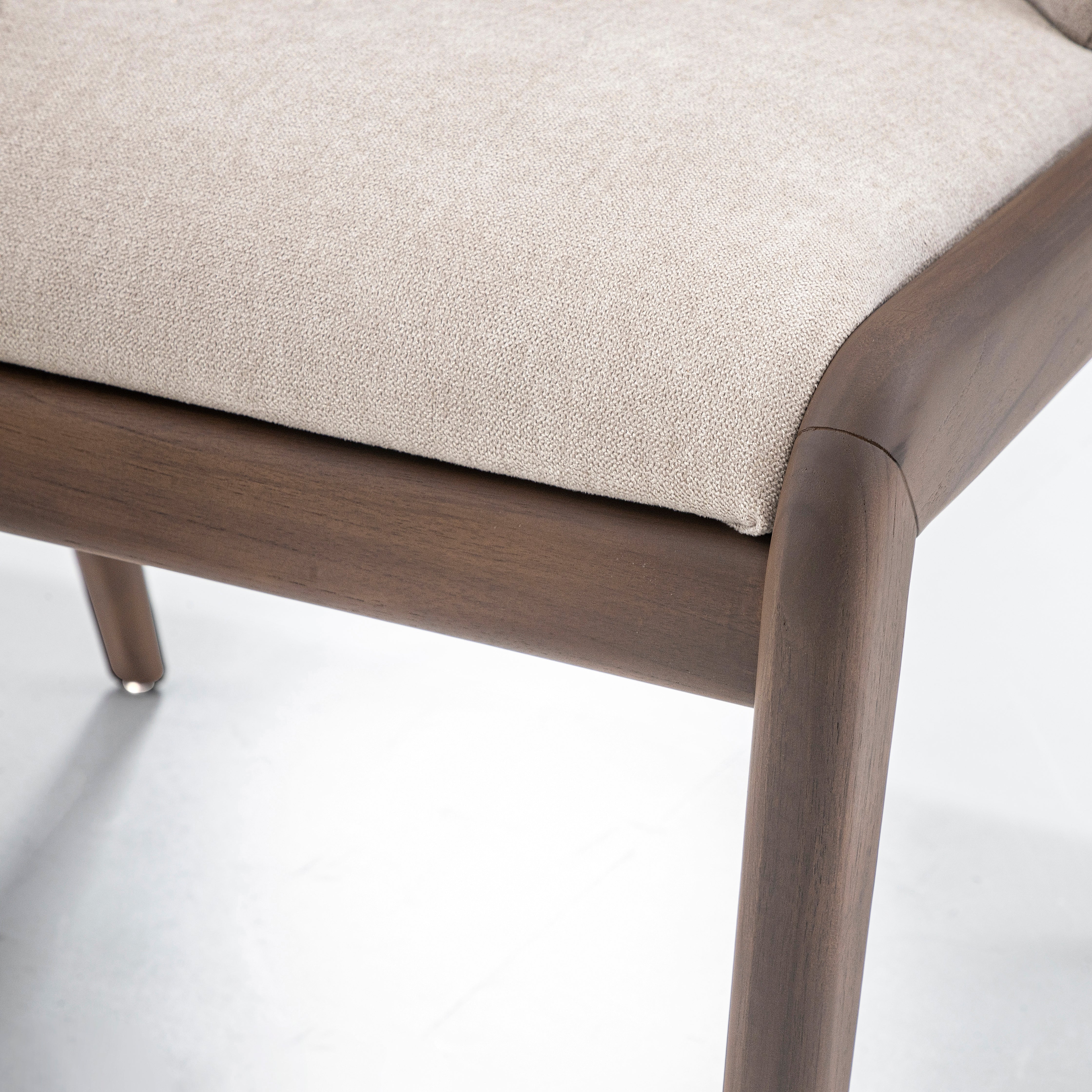 Close-up of a chair with wooden frame and beige cushion on a white background