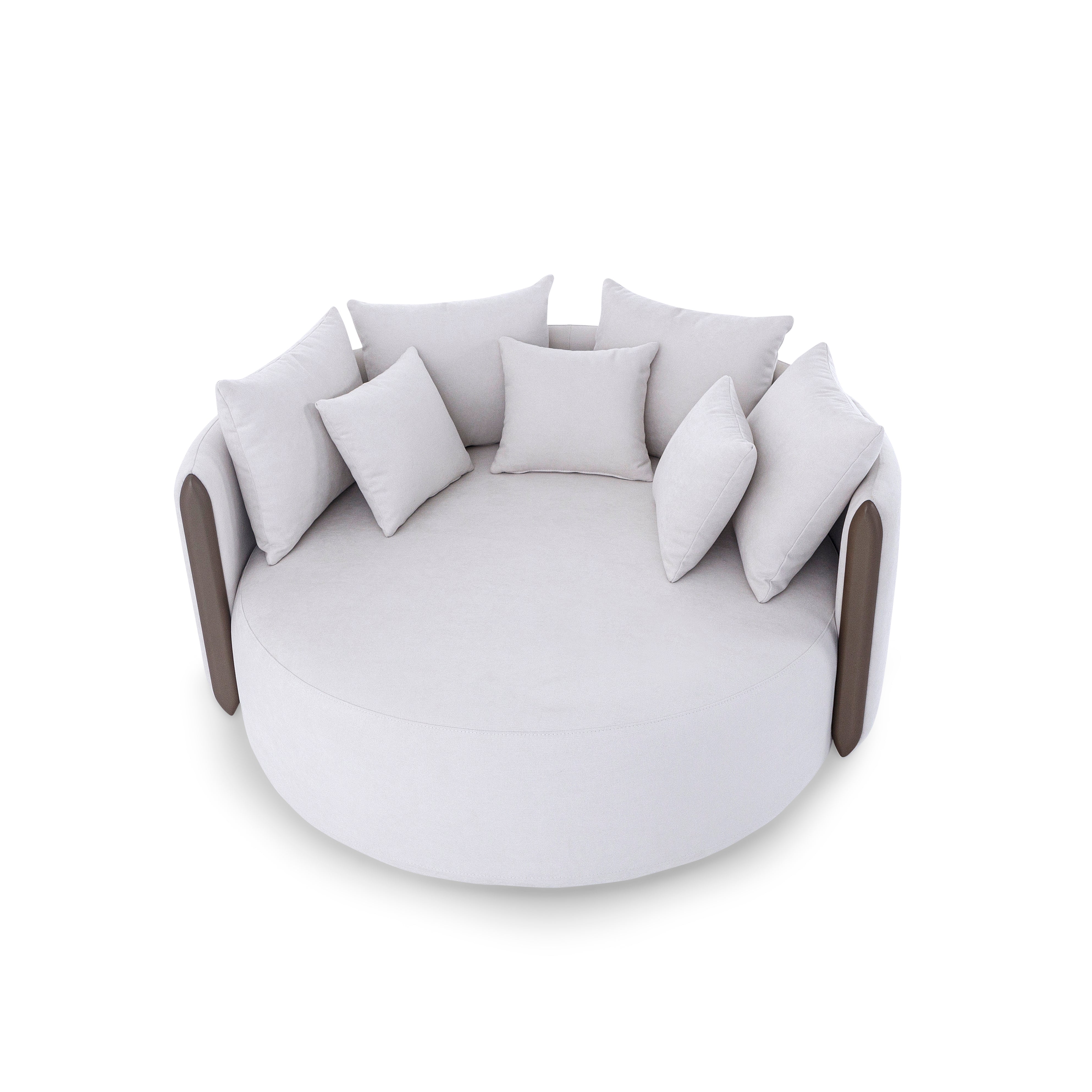 Round white sofa with multiple cushions on a white background