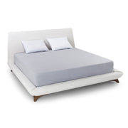 White bed with gray mattress cover and white pillows on a white background