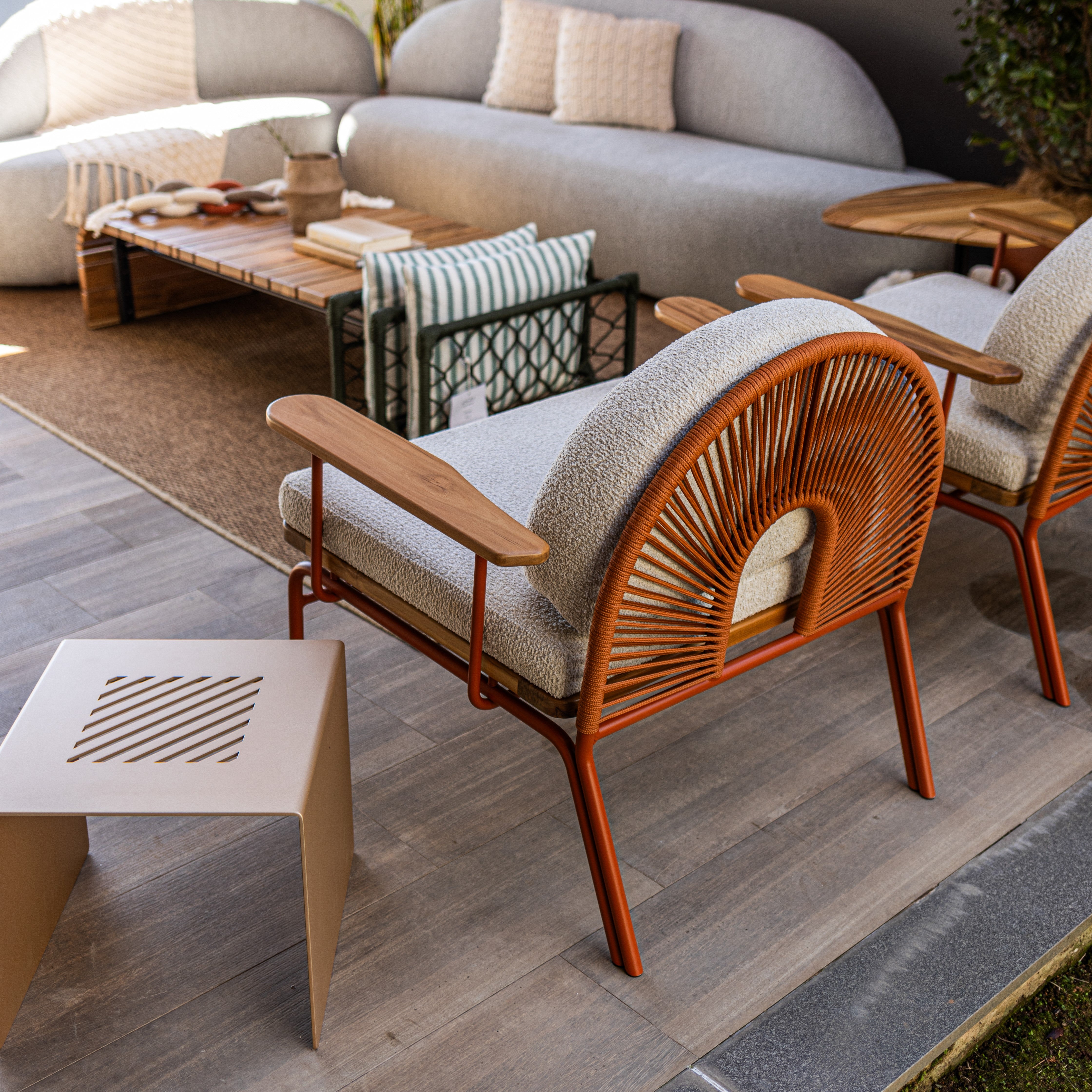 Modern outdoor furniture set with wooden chairs and a sofa on a stone patio.